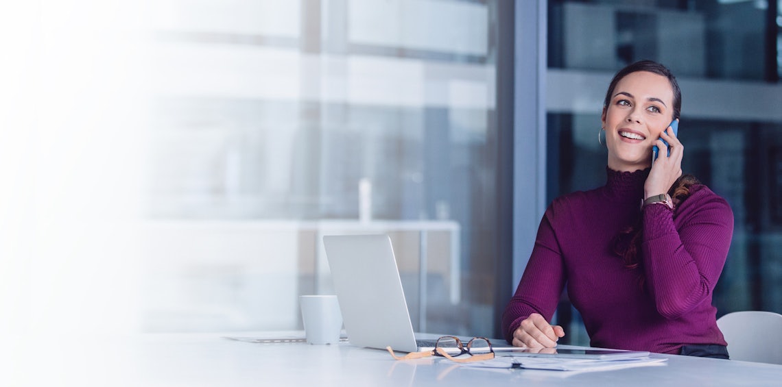 young sales professional sitting at her desk on the phone with a client using the consultative selling skills she learned in richardson's training program