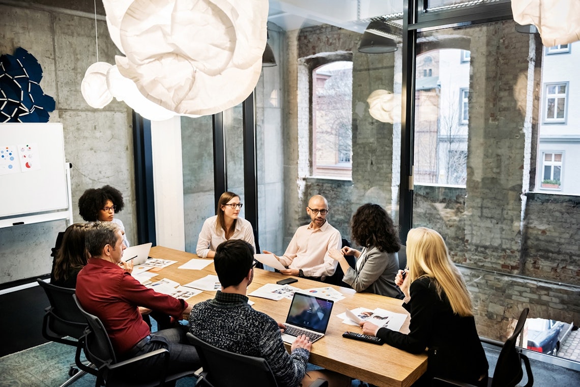 a diverse group of sellers and clients in a modern conference room having an engaging conversation because they have common experiences that create organic bonds within the group.