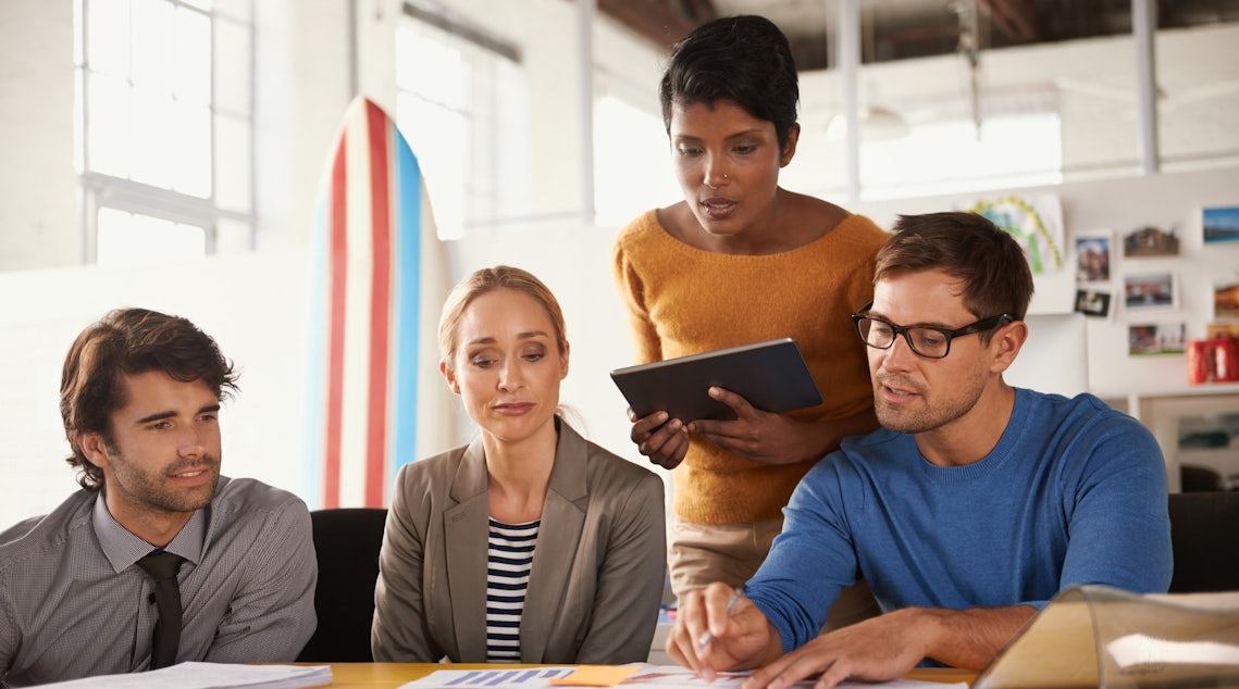 a sales enablement team huddled around a conference exploring a report measuring the performance of their efforts