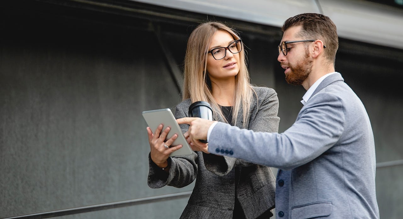 a female sales manager provides coaching and feedback to her male seller after a sales call in the field.