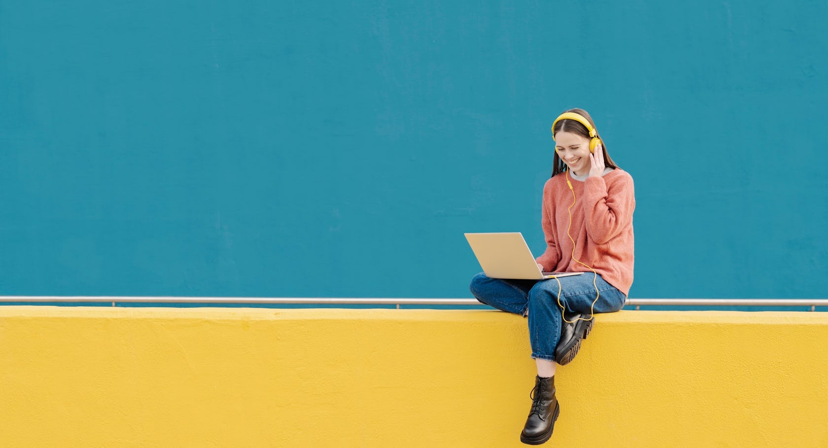young woman against a bright background on a laptop with headphones on - reading richardson's most recent social media posts