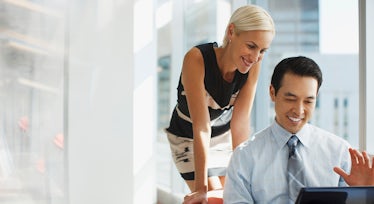 female sales leader standing behind her male sales rep as a metaphor for her helping him tap into the intrinsic motivation that will drive him to be more successful.