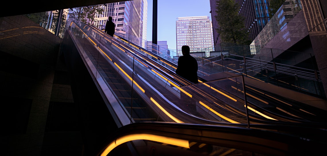 Person on outdoor escalator in dark corridor