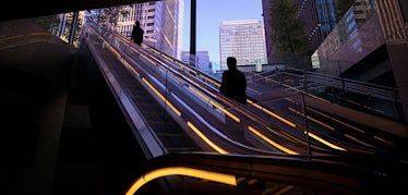 Person on outdoor escalator in dark corridor