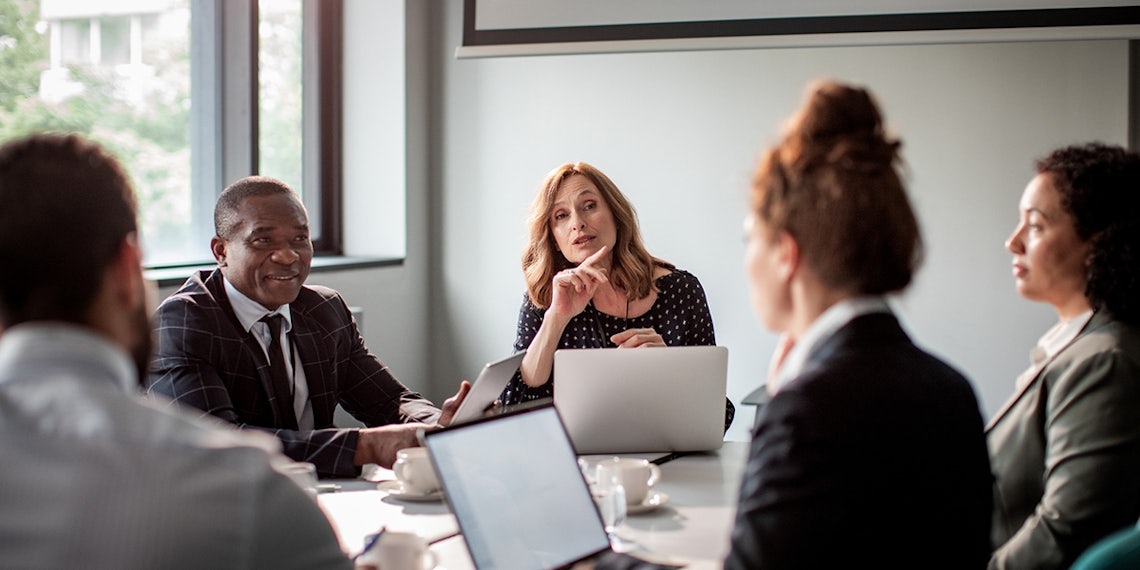 female sales manager speaking to her sales team in a conference room using practical sales management tips to drive performance