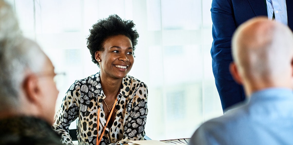 attractive black saleswoman engaging in a conversation with key decision makers that her effective sales skills and strategies have earned her access to.