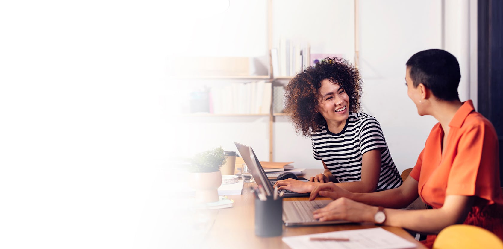 a young female sales professional and her manager sitting at a desk with a computer in an airy office working on their channel partner management plan using the skills they learned in richardson's channel partner management training program