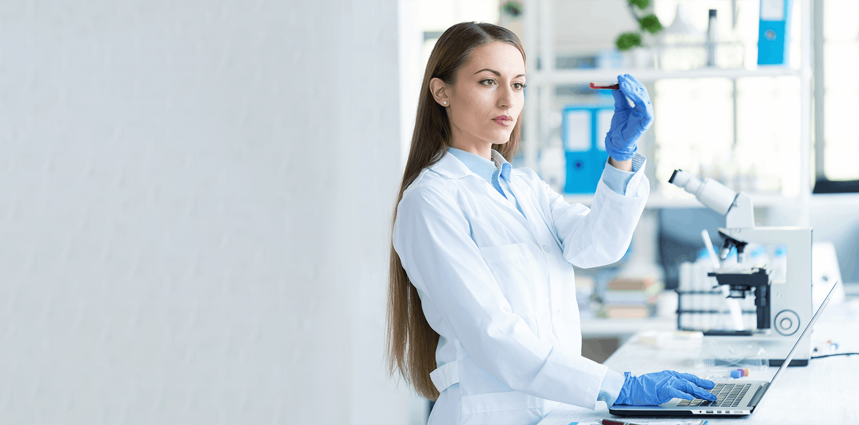 young female scientist using laptop and microscope in laboratory picture