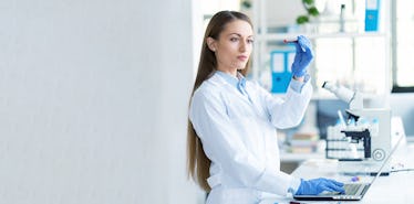 young female scientist using laptop and microscope in laboratory picture