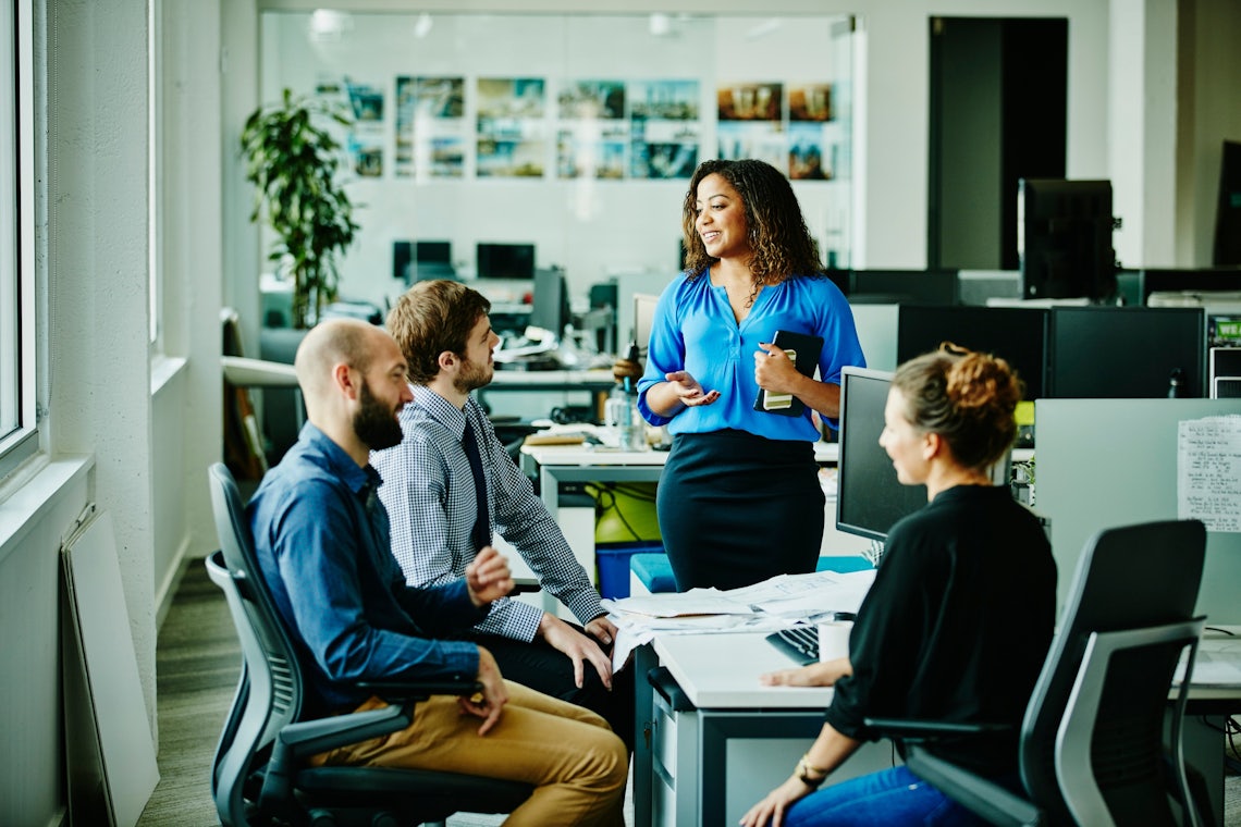 A sales manager addresses their team of three sales professionals helping to reinforce best practices learned in training to drive lasting behavior change.