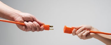 Two people holding up different ends of electrical plugs, symbolizing joining sales methodology with technology